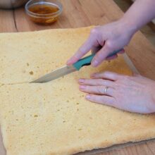 Blatul de pandișpan răcit se taie pe lungime în două foi egale, pentru asamblarea prăjiturii Diplomat la tavă