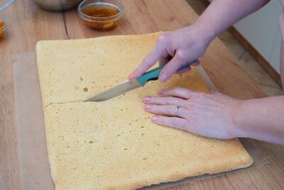 Blatul de pandișpan răcit se taie pe lungime în două foi egale, pentru asamblarea prăjiturii Diplomat la tavă