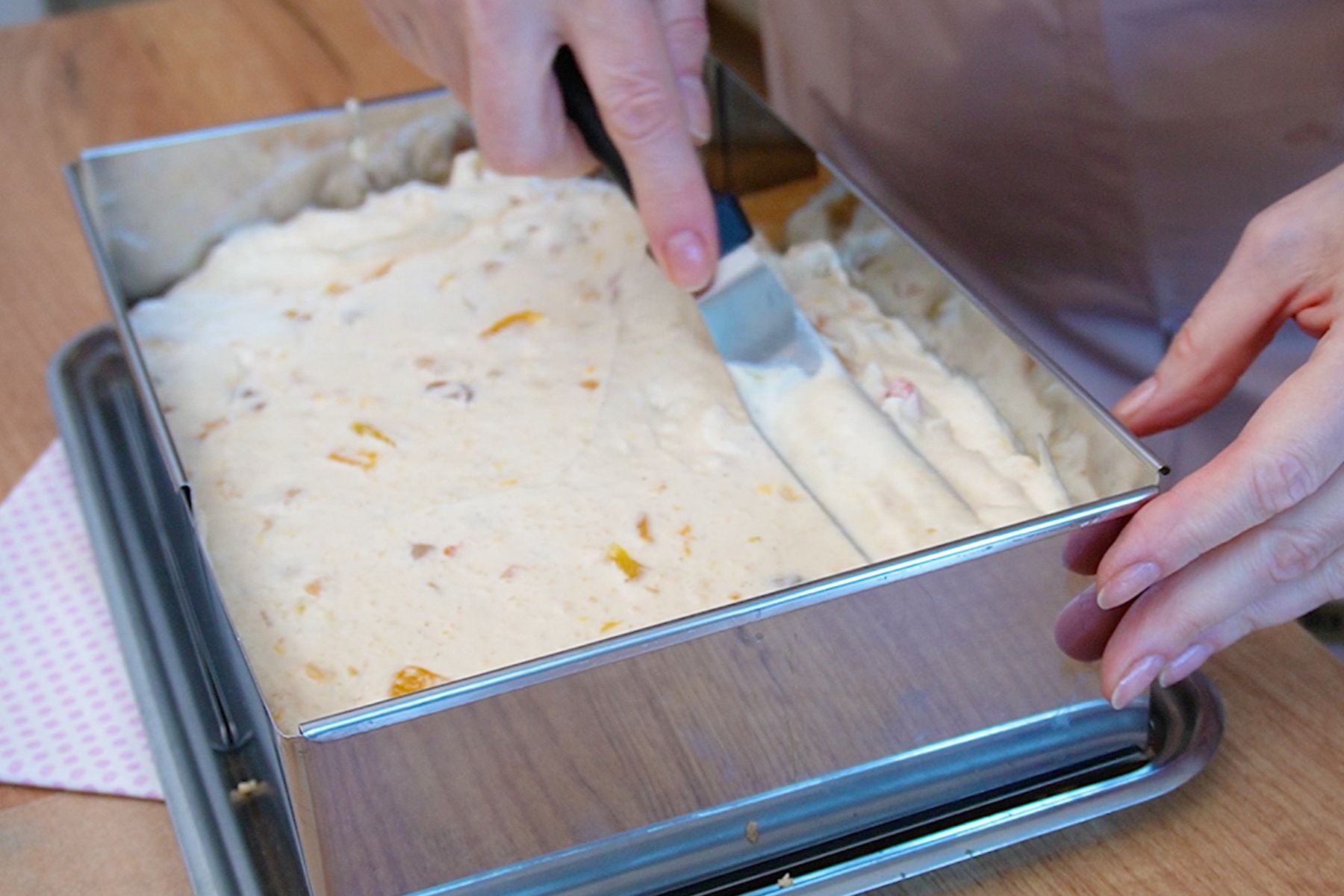 Crema Diplomat cu fructe exotice este turnată și nivelată peste primul blat, în cadrul pentru montarea prăjiturii la tavă