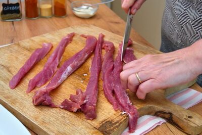 Mușchiuleț de porc tăiat în fâșii lungi și inegale pentru rulada mozaic în prosciutto