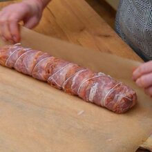 Ruladă din mușchiuleț de porc legată cu sfoară și învelită în hârtie de copt înainte de coacere