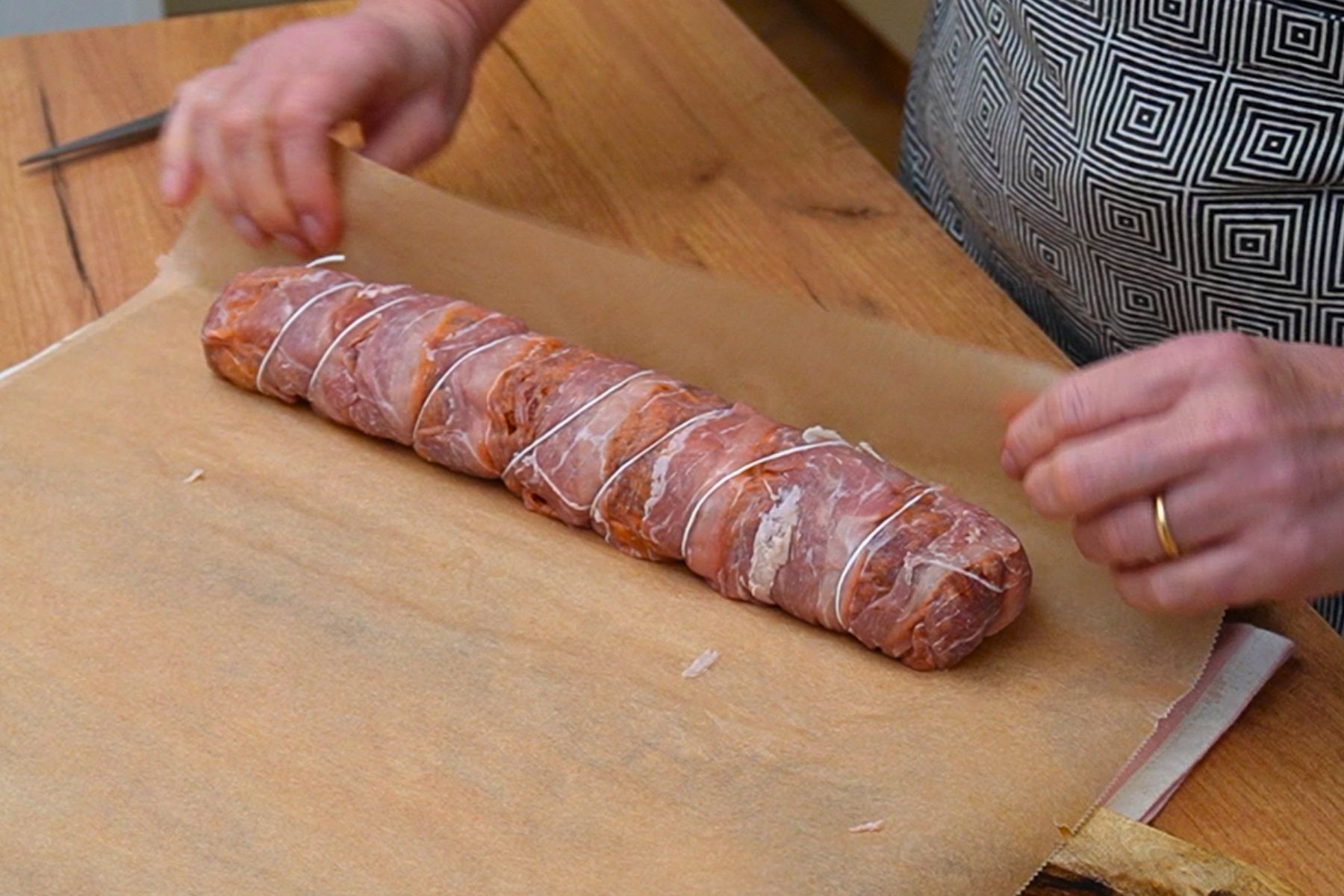 Ruladă din mușchiuleț de porc legată cu sfoară și învelită în hârtie de copt înainte de coacere