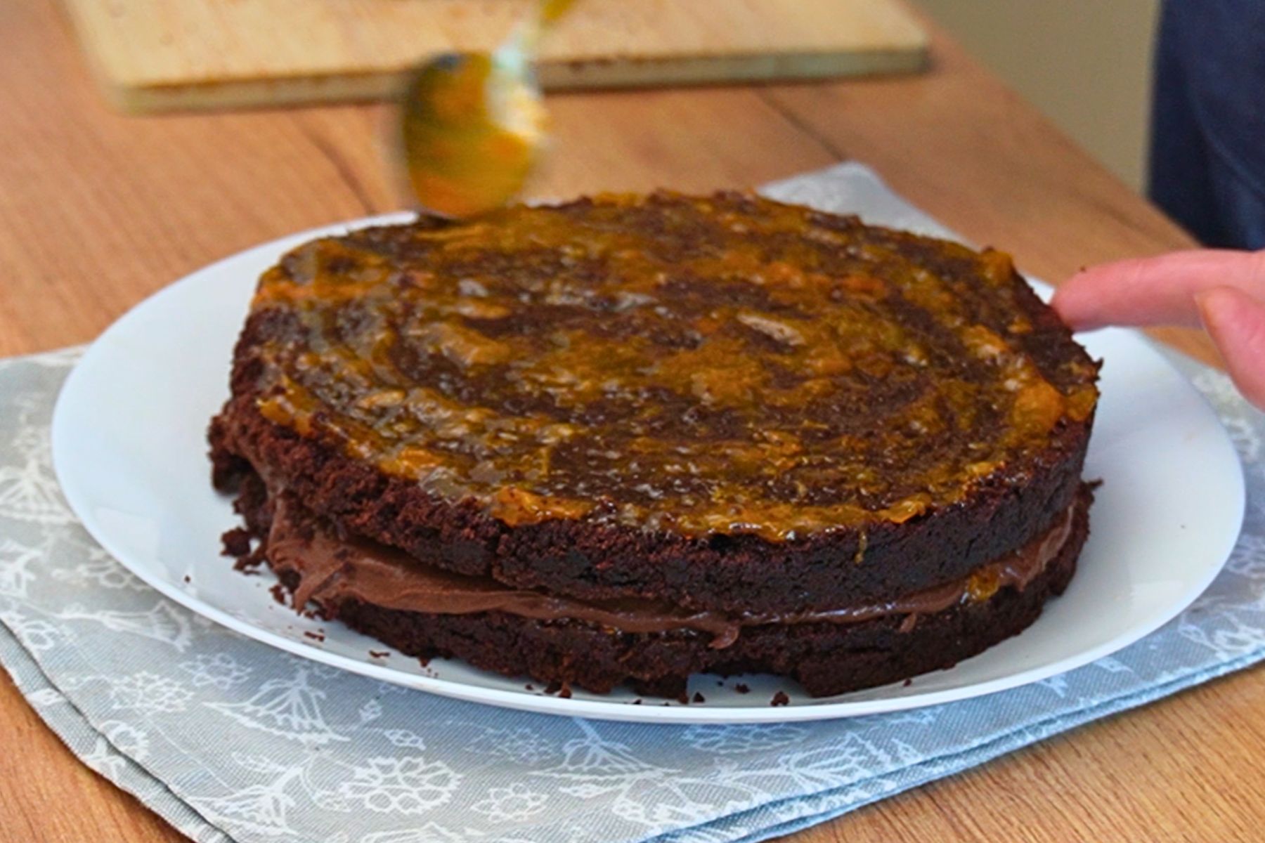 Gem de caise întins pe al doilea blat la asamblarea tortului de post cu ciocolată și gem de caise