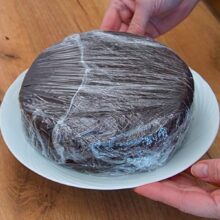 Blat de tort de post cu ciocolată învelit în folie alimentară și lăsat la răcit înainte de tăiere