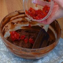 Cireșe confiate tocate adăugate în crema de ciocolată cu cocos pentru tortul de post cu ciocolată