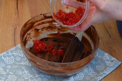 Cireșe confiate tocate adăugate în crema de ciocolată cu cocos pentru tortul de post cu ciocolată