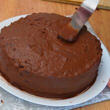 Tort de post cu ciocolată acoperit cu cremă fină de ciocolată înainte de decorare