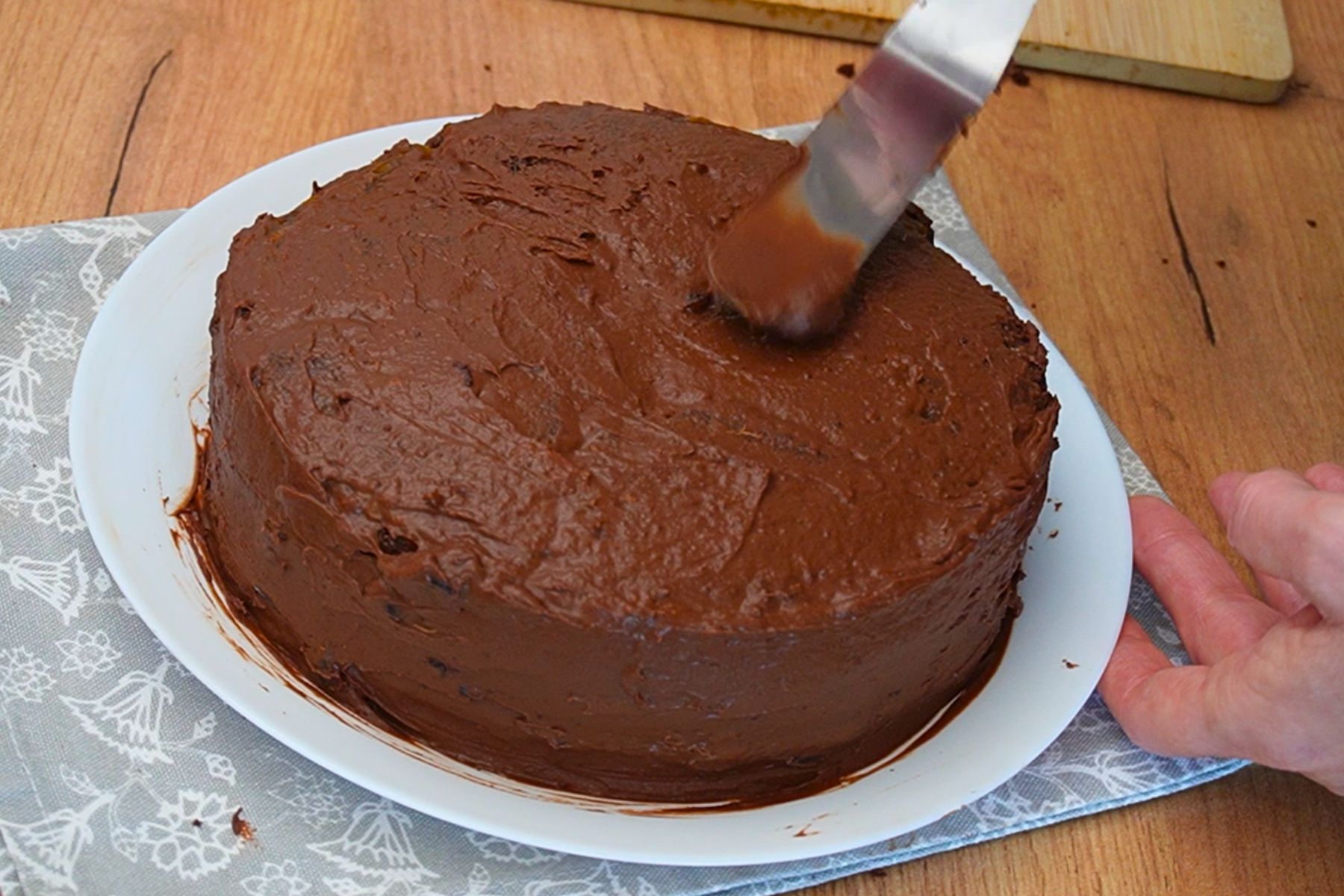 Tort de post cu ciocolată acoperit cu cremă fină de ciocolată înainte de decorare