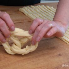 Modelarea covrigilor polonezi din aluat împletit, pe masa de lucru din lemn