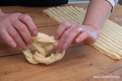 Modelarea covrigilor polonezi din aluat împletit, pe masa de lucru din lemn