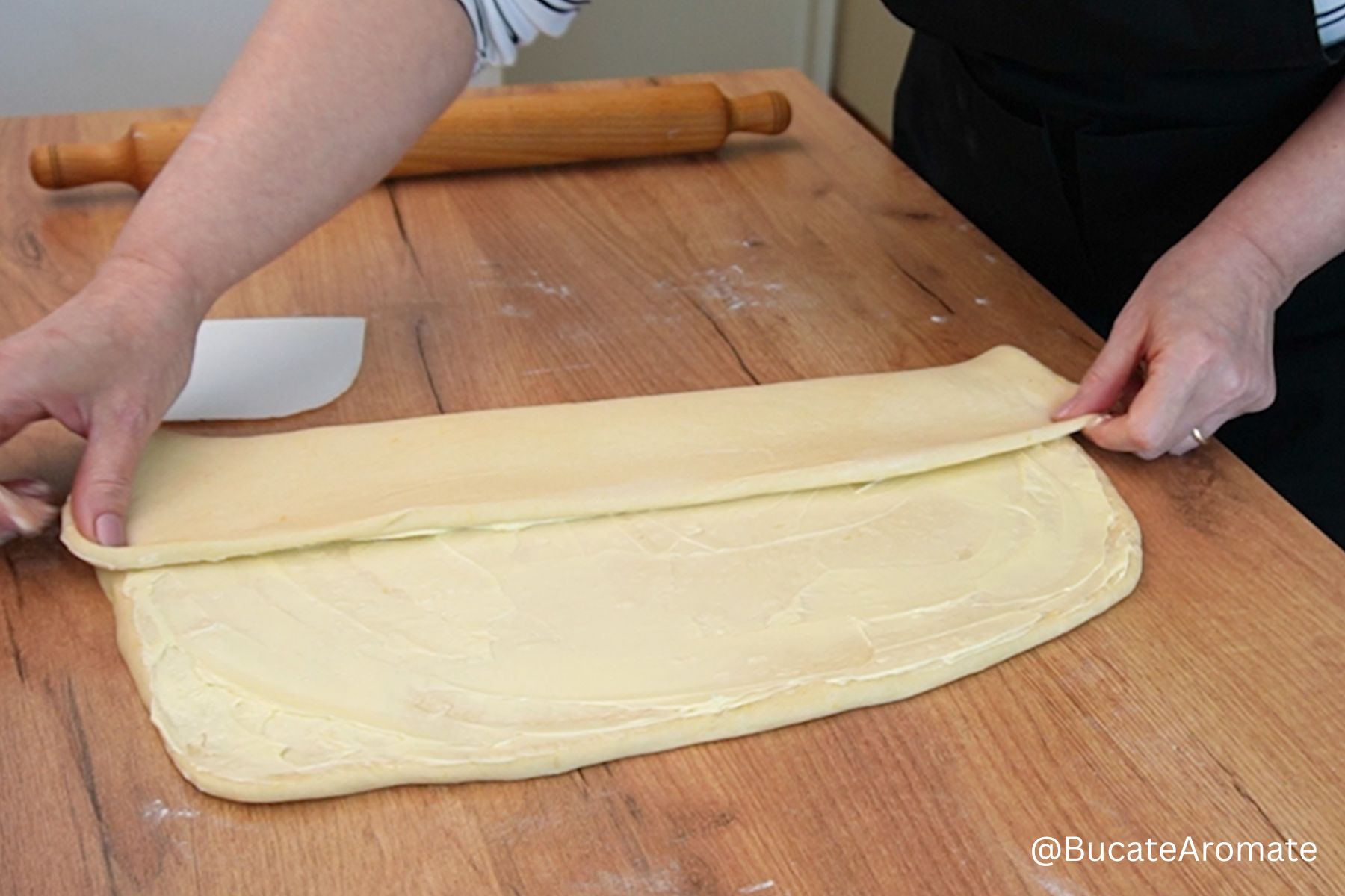 Împăturirea aluatului uns cu unt pentru covrigi polonezi, pe blatul de lucru