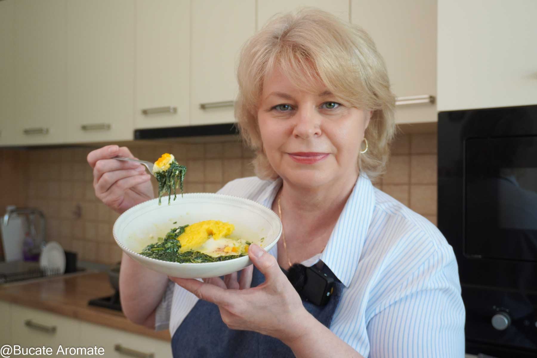 Iuliana de la Bucate Aromate ținând în mână un bol cu spanac cremos cu lapte, ou moale și mămăligă, gata de servire