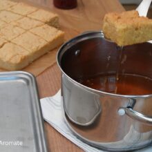 O bucată de blat pentru savarine cu pesmet la tavă este trecută prin sirop aromat, înainte de montare.
