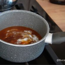 Zahărul caramelizat fierbe într-o crăticioară, pregătit pentru siropul aromat al savarinelor cu pesmet la tavă.