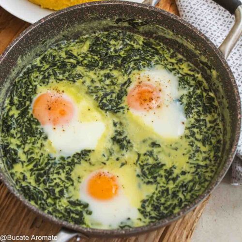 Prim-plan cu spanac cremos și 3 ouă moi făcute direct în tigaie, presărate cu piper