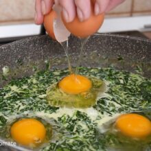 Ouă sparte direct în tigaie peste spanacul cu lapte, înainte de gătirea sub capac