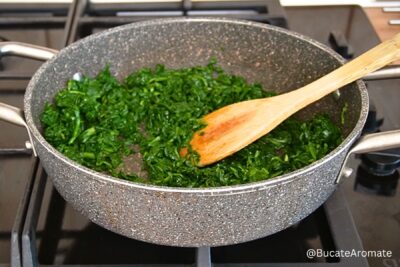 Spanac sotat în unt într-o tigaie adâncă, înainte de adăugarea sosului de lapte