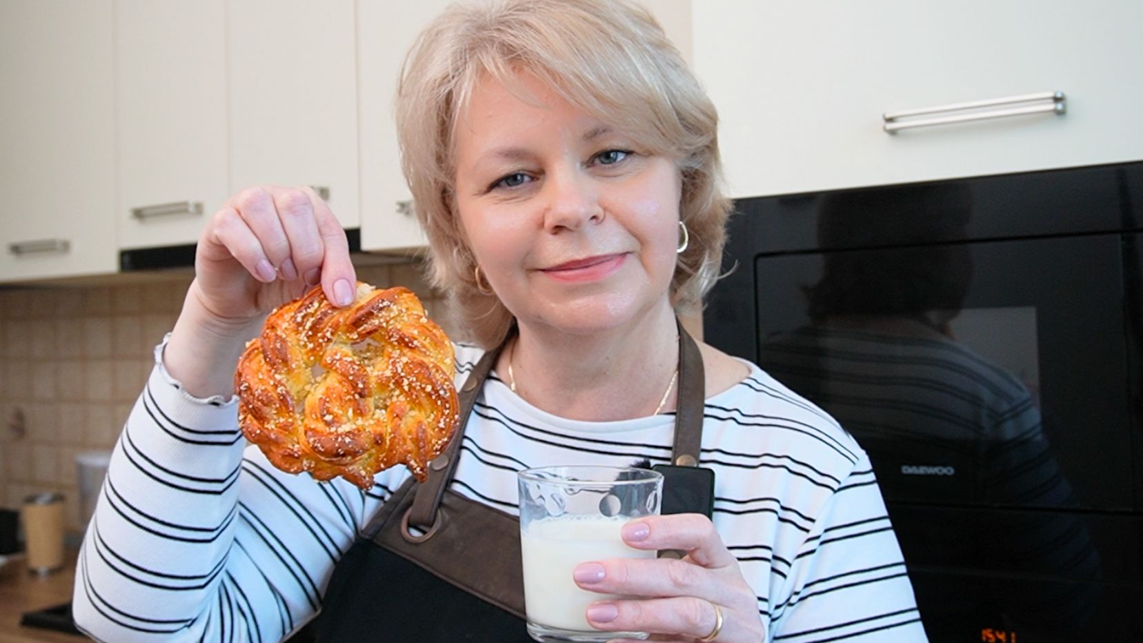 Iuliana Sbirnea autoarea Bucate Aromate în bucătărie, ținând în mâini un covrig polonez si un pahar cu lapte