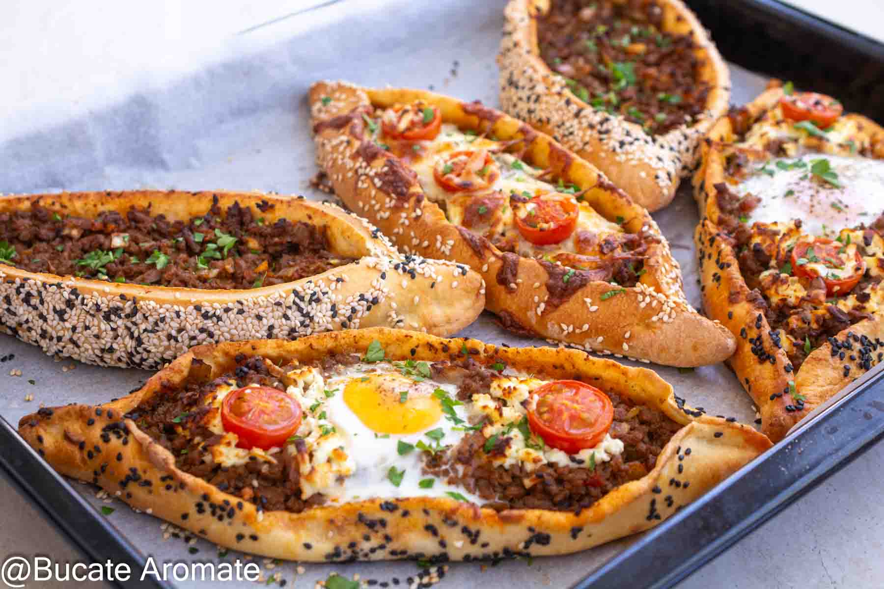 Pide turcești cu carne tocată de vită, umplutură suculentă, ou moale, telemea și roșii cherry, coapte pe hârtie de copt.