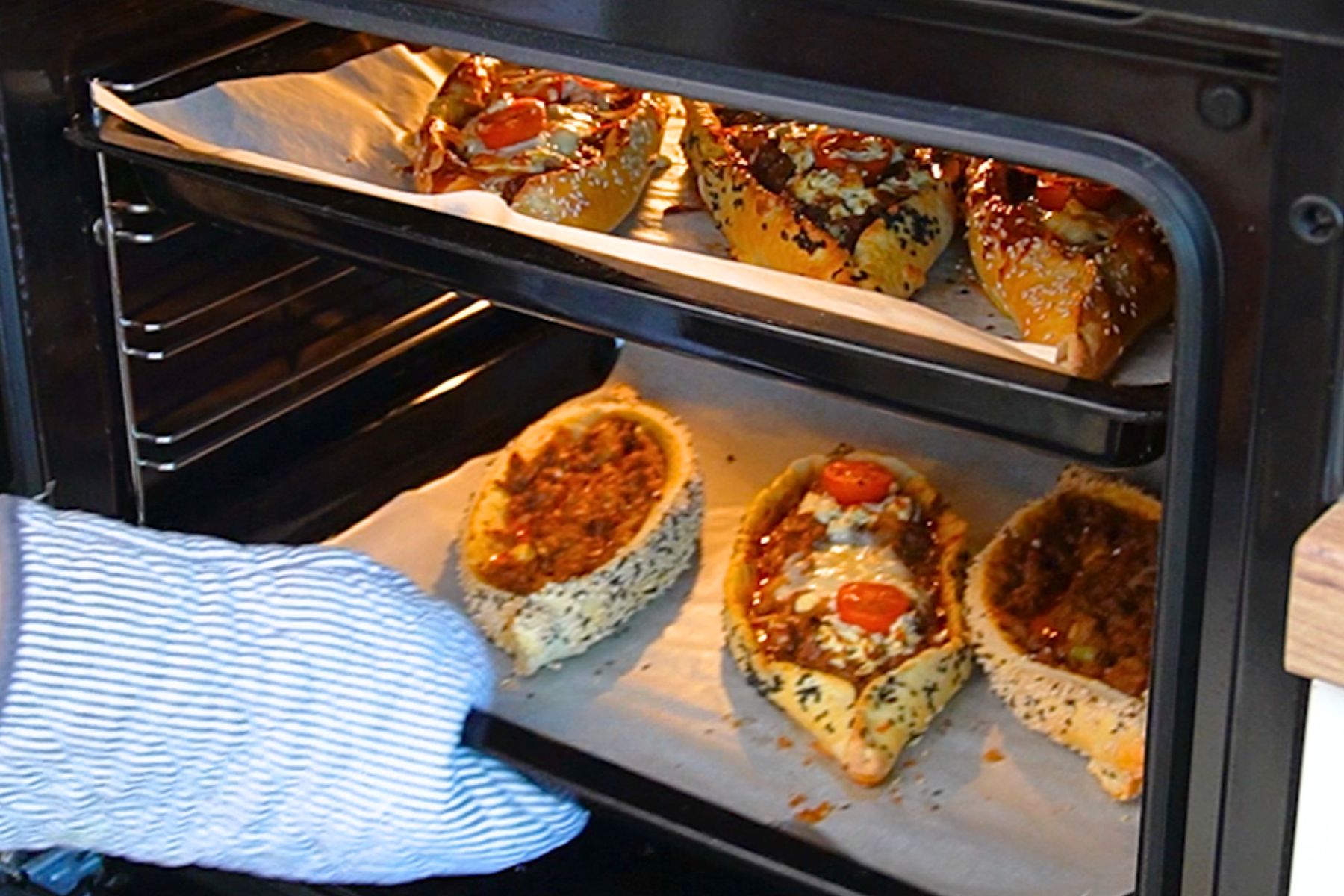 Pide turcești cu carne tocată de vită coapte în cuptor, cu aluat rumenit și umplutură de carne și brânză.