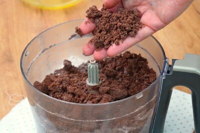 Aluat fraged cu cacao, pregătit la robot, cu textură nisipoasă pentru prăjitura Rudy cu brânză și căpșuni.