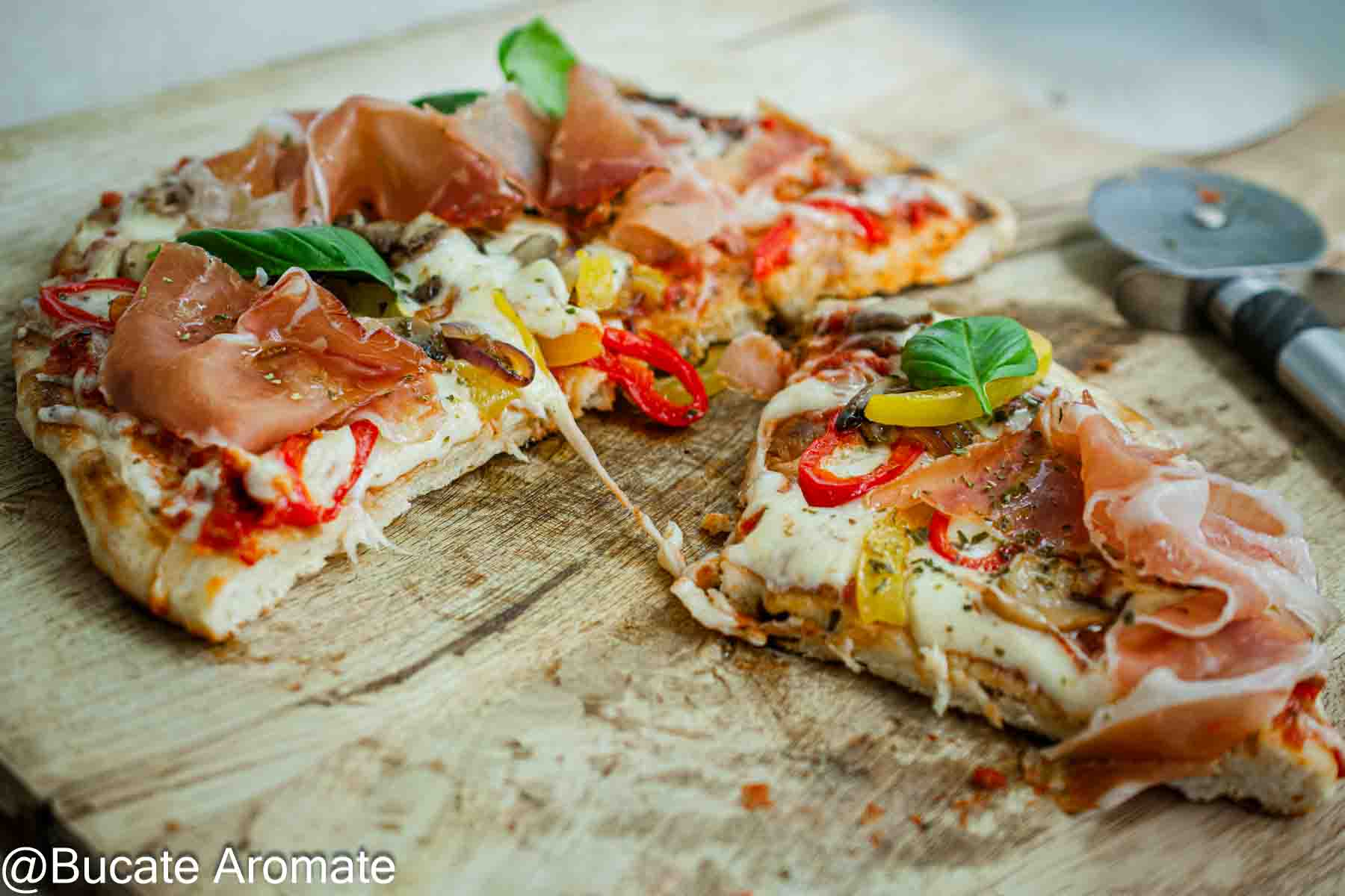 Felii de pizza la tigaie cu blat subțire, cașcaval topit, ardei, ciuperci, prosciutto crudo și frunze de busuioc.