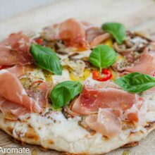 Pizza rapidă la tigaie cu praf de copt, servită pe tocător, cu blat subțire, legume călite, cașcaval topit și prosciutto crudo.