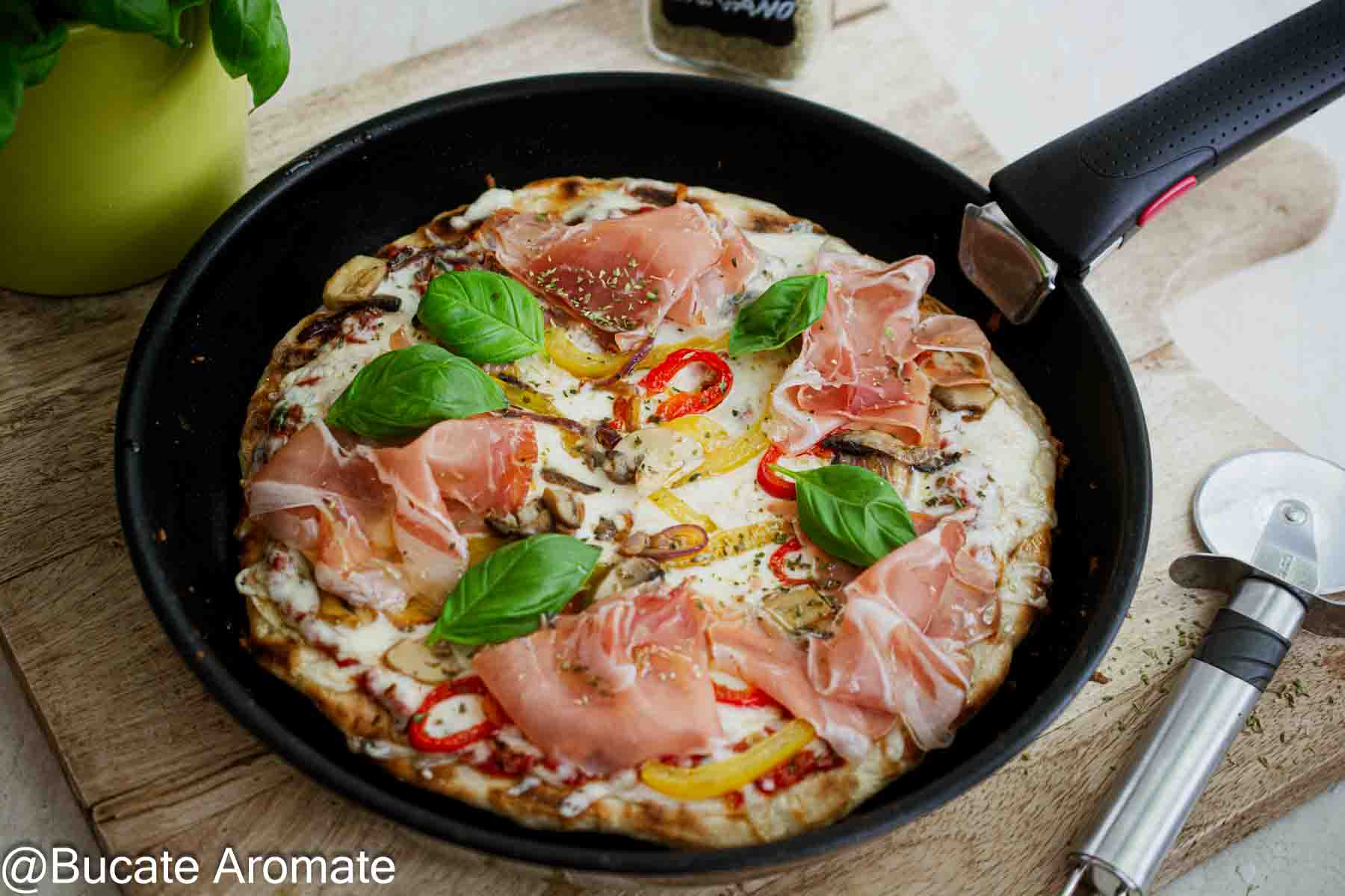 Pizza fără drojdie pregătită în tigaie, cu cașcaval topit, ardei, ceapă roșie, ciuperci, prosciutto crudo și busuioc proaspăt.
