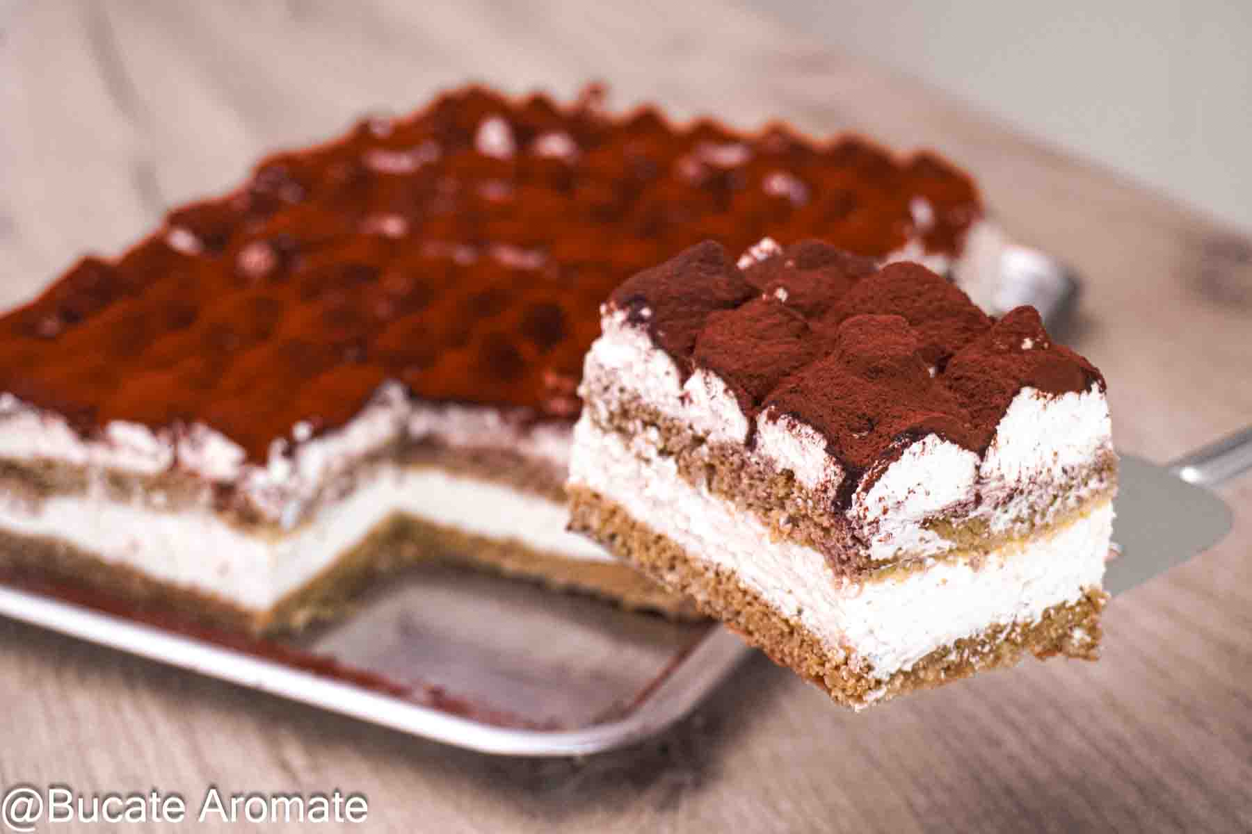 Porție de prăjitură Tiramisu fără pișcoturi, cu blat de casă, cremă de mascarpone și cacao, ridicată pe paletă din tavă