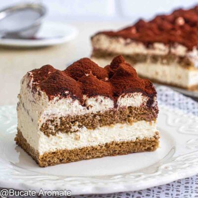 Felie de prăjitură Tiramisu la tavă, cu două straturi de blat însiropat, cremă de mascarpone și decor cu cacao