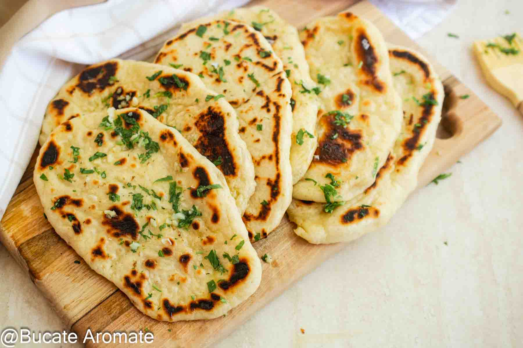Lipii indiene naan cu drojdie, coapte în tigaie și servite calde cu usturoi și verdeață