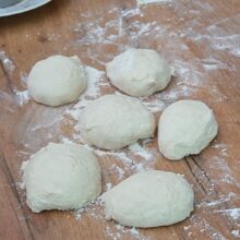 Aluat pentru naan împărțit în 6 bucăți egale, pe blatul presărat cu făină, înainte de modelarea lipiilor