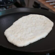 Lipie naan pusă la copt într-o tigaie bine încinsă, fără ulei