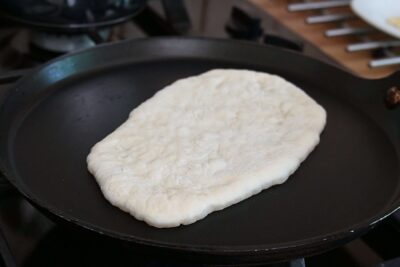 Lipie naan pusă la copt într-o tigaie bine încinsă, fără ulei
