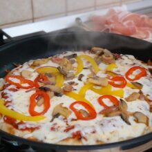 Pizza la tigaie cu cașcaval topit, ardei roșu și galben, ceapă și ciuperci călite.
