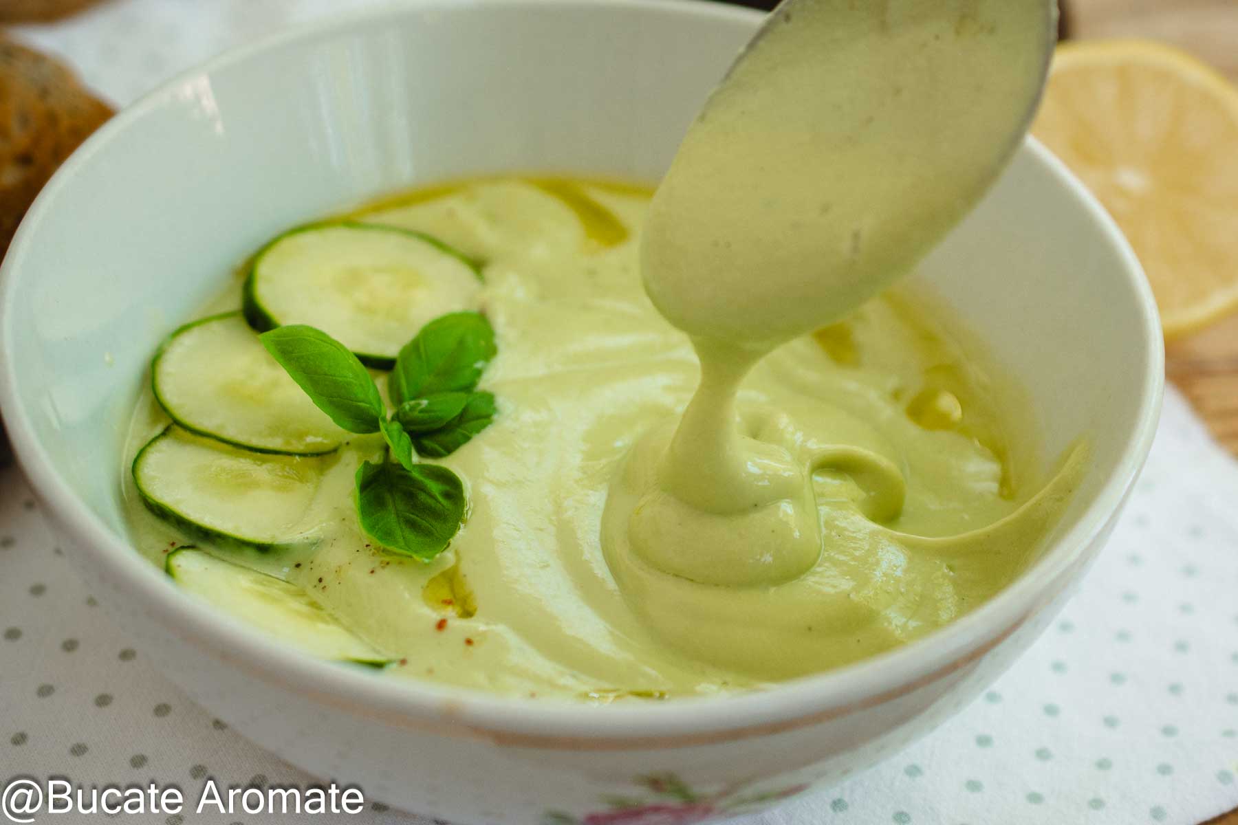 Textură cremoasă de supă rece de avocado cu iaurt, servită cu felii de castravete, busuioc și ulei de măsline