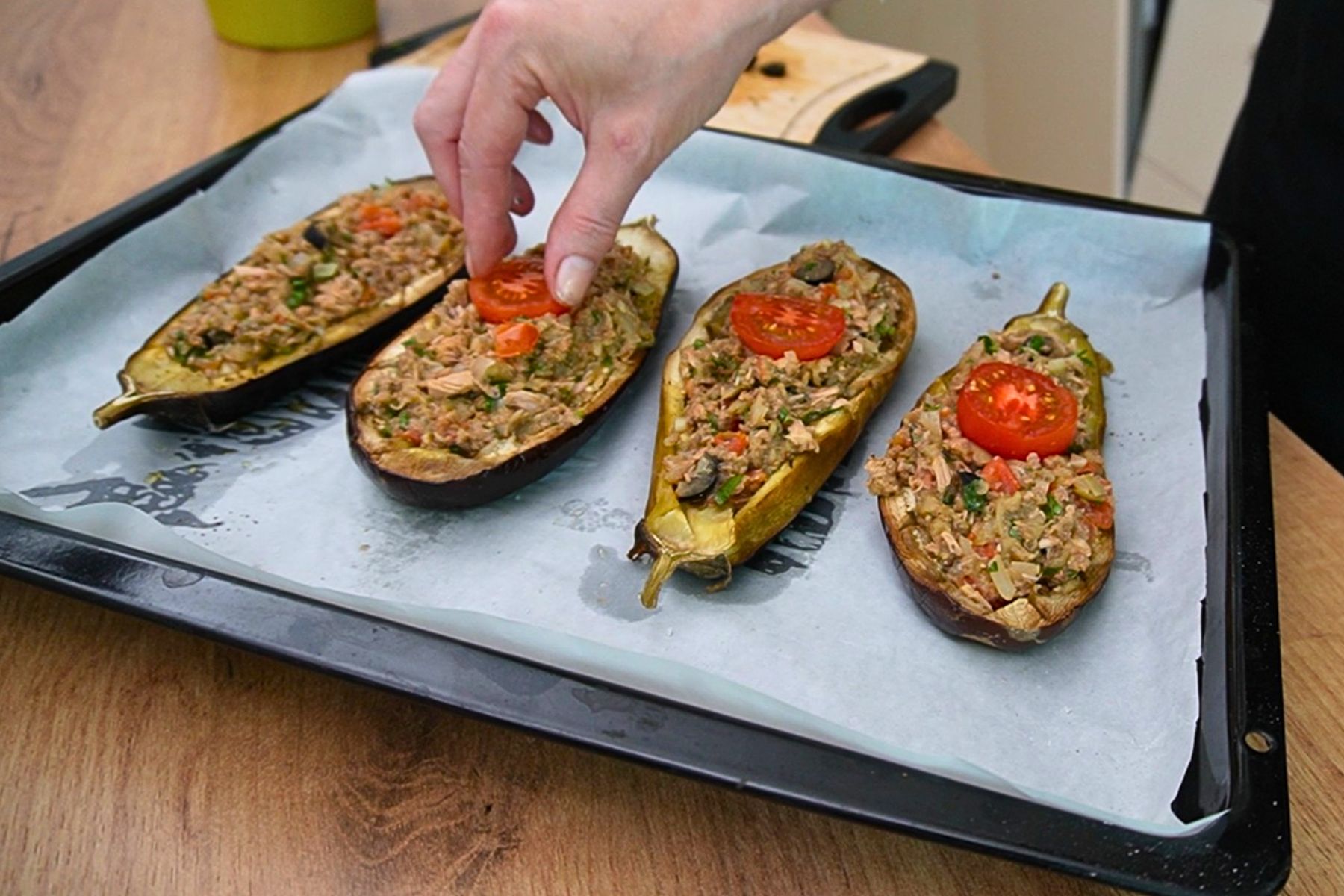 Jumătăți de vinete umplute cu compoziție de ton, legume și măsline, înainte de coacerea finală.