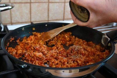 Carne tocată de pui gătită în sos de roșii cu ceapă, usturoi, boia și condimente, amestecată în tigaie.