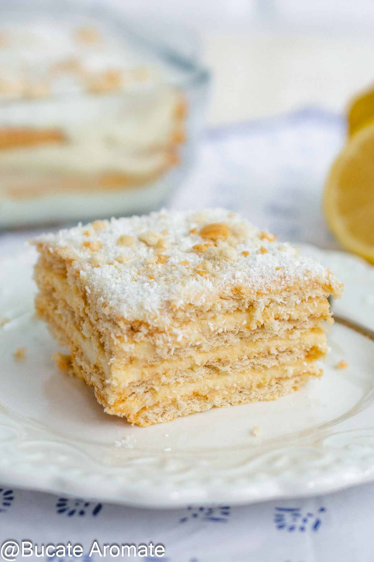 Felie de prăjitură rapidă cu biscuiți, cremă de lămâie și lapte condensat, decorată cu cocos și biscuiți sfărâmați