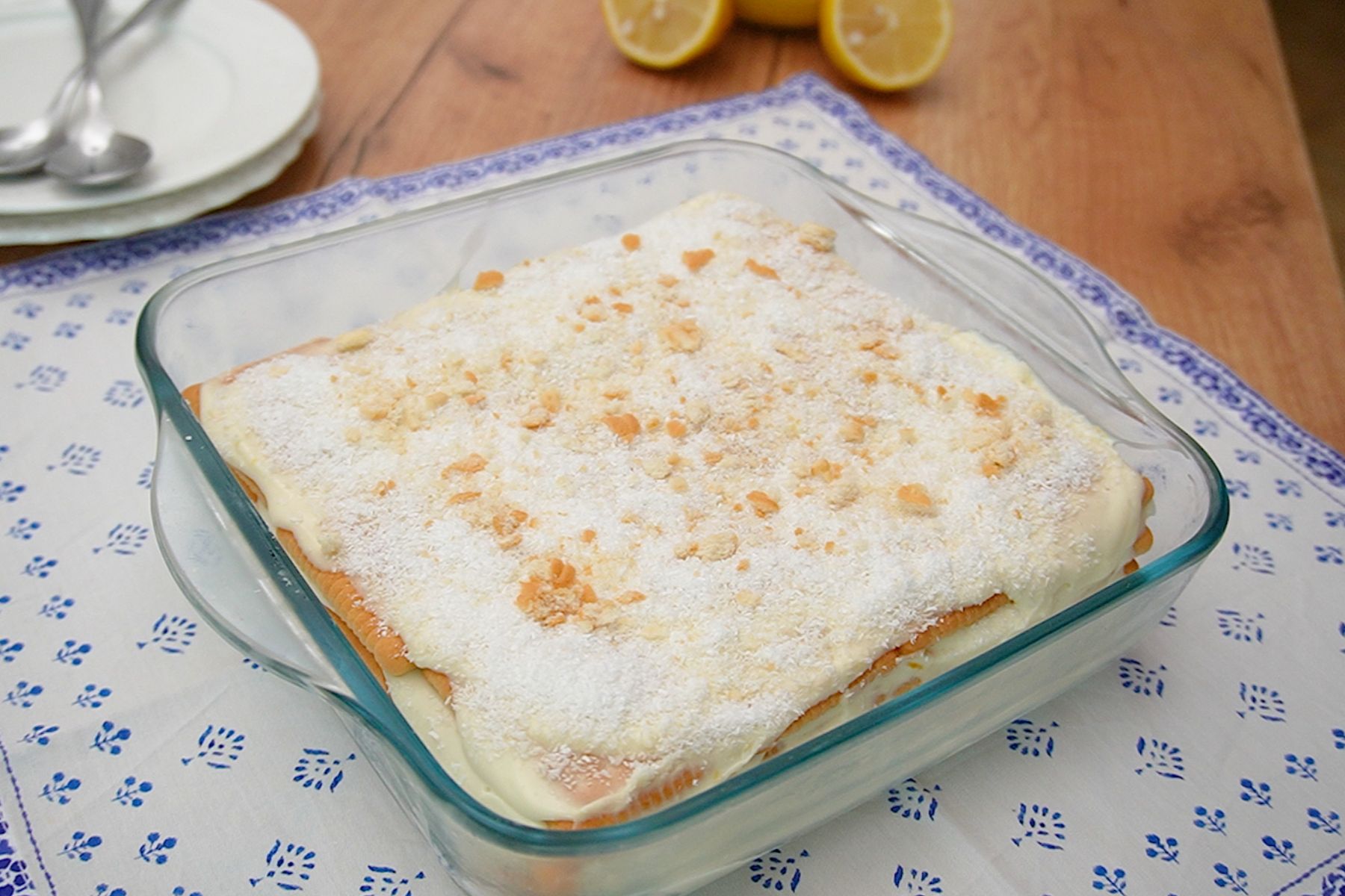 Prăjitură fără coacere cu biscuiți și cremă de lămâie, decorată cu fulgi de cocos și biscuiți mărunțiți