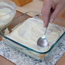 Cremă fină de lămâie întinsă peste stratul de biscuiți Petit Beurre într-o tavă pătrată