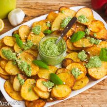Cartofi rondele la cuptor cu pesto de busuioc și caju, serviți pe platou cu lămâie și usturoi