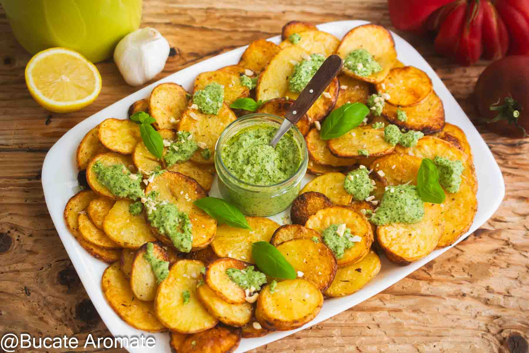 Cartofi rondele la cuptor cu pesto de busuioc și caju, serviți pe platou cu lămâie și usturoi