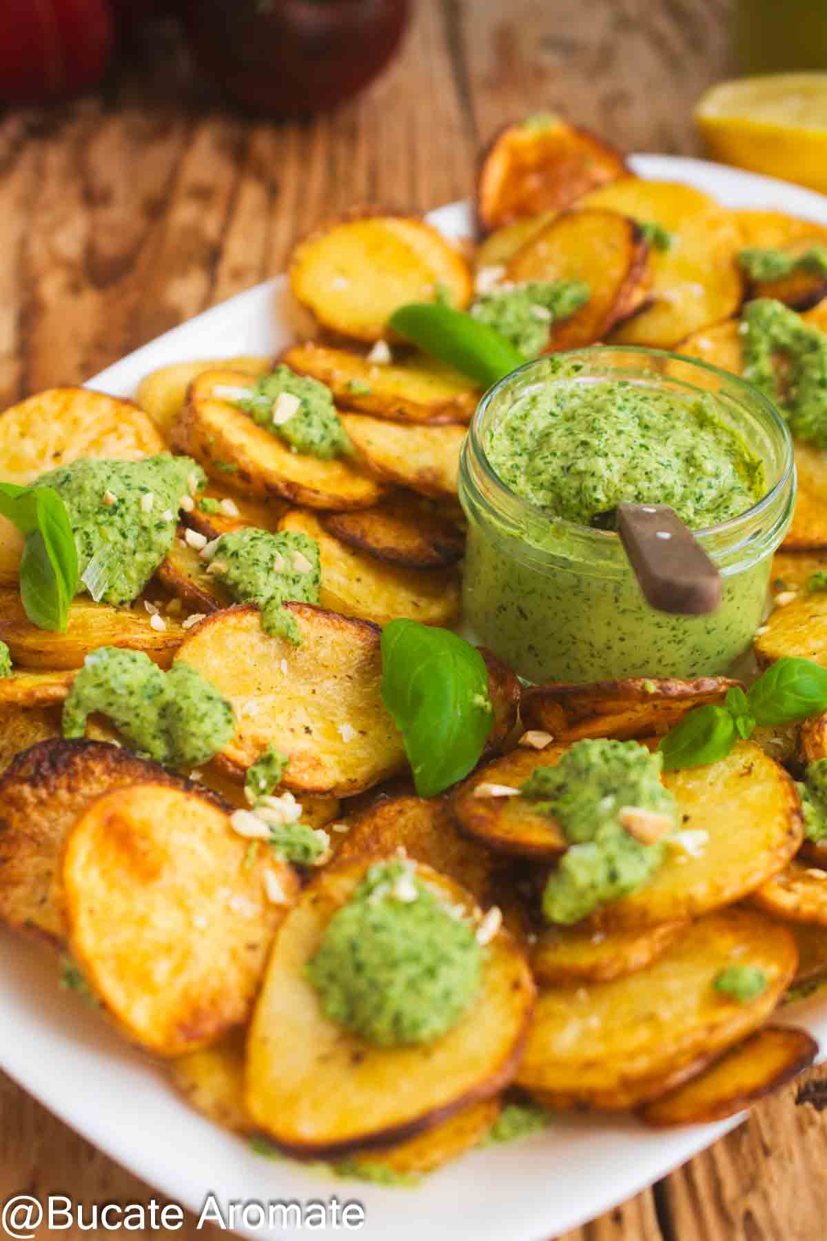 Rondele de cartofi coapte, cu pesto vegan de busuioc și caju, decorate cu frunze proaspete