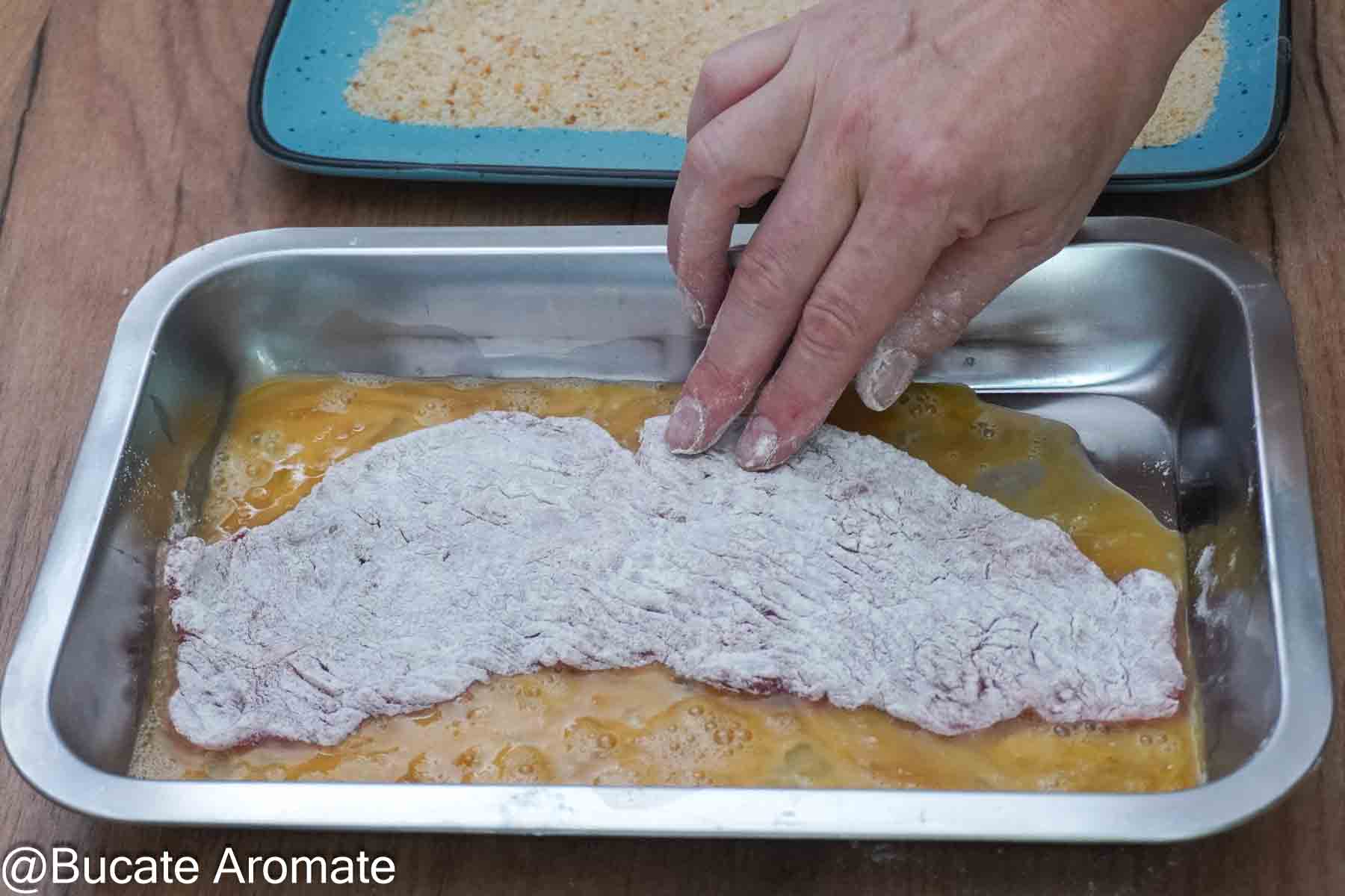 Felie de vițel acoperită cu făină, trecută prin ou bătut într-un vas dreptunghiular