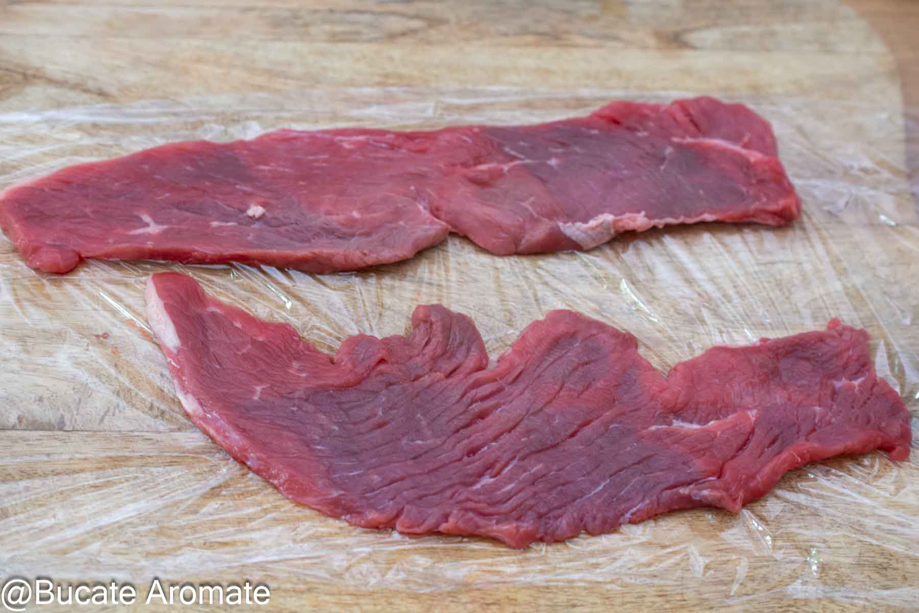 Două felii lungi și foarte subțiri de carne de vițel, pregătite pentru șnițel vienez