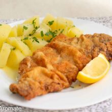 Șnițel vienez cu panadă aurie și încrețită, servit cu cartofi natur și lămâie