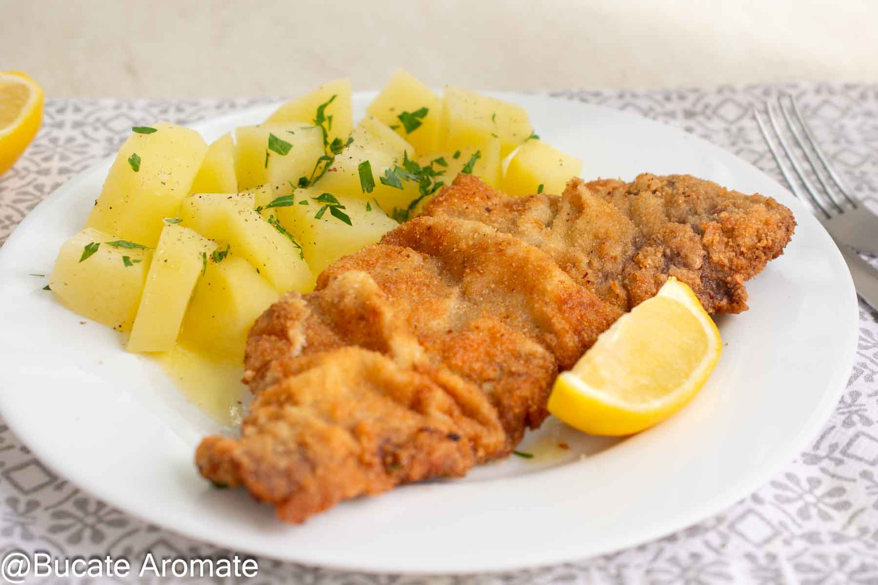 Șnițel vienez cu panadă aurie și încrețită, servit cu cartofi natur și lămâie