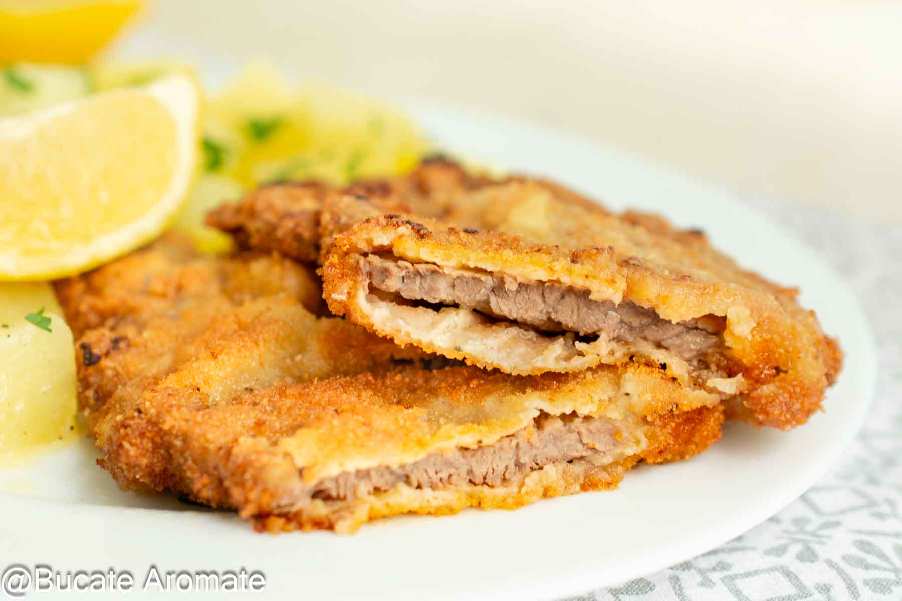 Șnițel vienez tăiat în secțiune, cu carne subțire de vițel și crustă aerată, desprinsă de carne