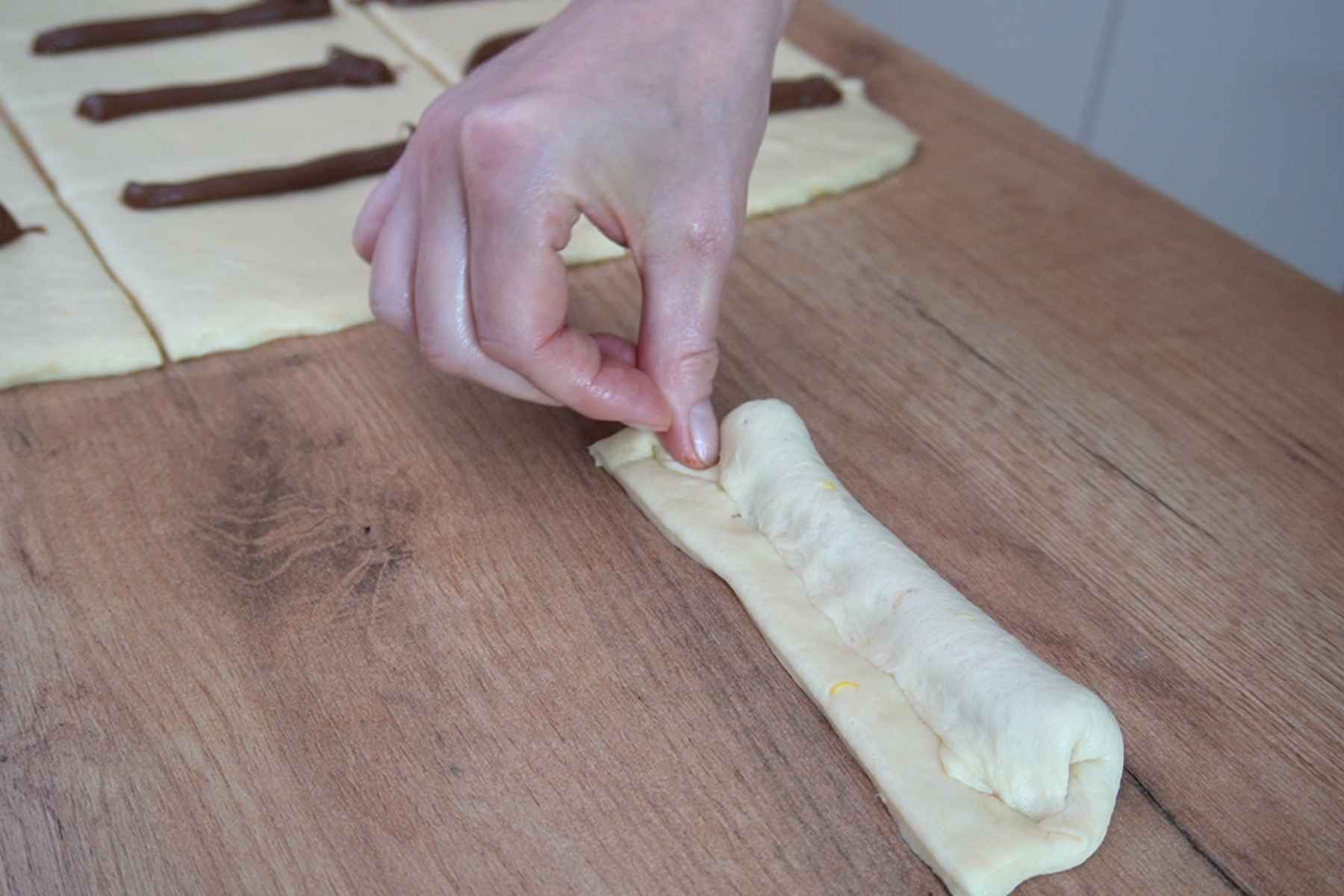 Sigilarea aluatului peste umplutura de ciocolată pentru gogoși baton